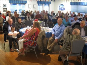 Roseman and his family (left foreground) are surrounded by the many friends and well-wishers who packed the Pentwater Yacht Club dining room Thursday evening.